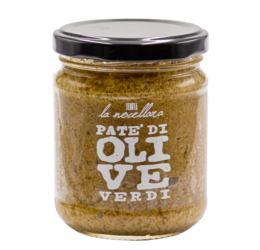 Green olive pâté in a glass jar, with bread slices and a piece of bread on a wooden surface.