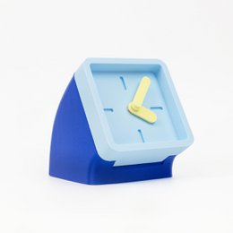  A small, square wall clock in a blue and light blue color scheme, with a yellow clock hand.
