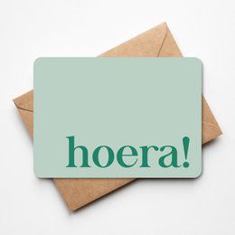 Greeting card with the text "hoera!" in green on a mint green background, accompanied by a brown envelope.