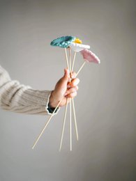  Bouquet of 4 chamomile flowers in pastel colors including turquoise, yellow, and pink. The flowers are held in a person's hands against a neutral background.