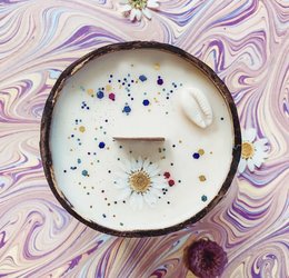 Coconut shell candle with a rustic, natural design featuring a sun and stars motif.