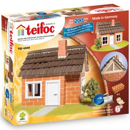 A half-timbered house construction kit for kids, featuring bricks, tiles, and other building materials in various shapes and colors. The kit allows children to build a realistic-looking miniature house.