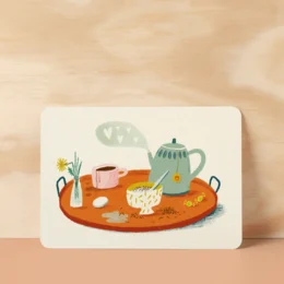 A postcard with an illustration of a breakfast tray with a teapot, cup, and other breakfast items on an orange surface.