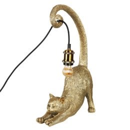 Gold-colored table lamp in the shape of a cat, with a curved body and a lamp fixture attached to the back. The lamp has a textured, metallic finish that gives it a decorative, sculptural appearance.