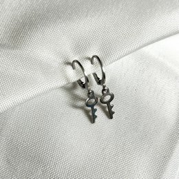 Silver hoop earrings with a key-shaped charm.