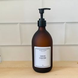  Glass bottle with black pump dispenser, containing liquid soap. Amber-colored glass bottle with simple, minimalist label design.