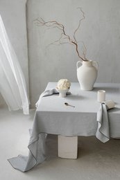 Off-white linen tablecloth, 250x145 cm, with a minimalist floral centerpiece arrangement on a white table.