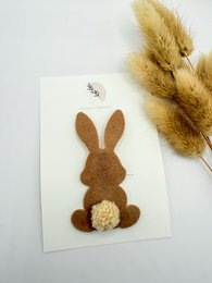  A brown felt rabbit-shaped hair clip with a fluffy white pom-pom accent, suitable for children's hair accessories.