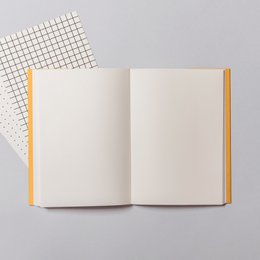 A notebook with a textured cover in various neutral colors including blue, yellow, rust, green, concrete, and lavender. The notebook has an embossed design on the cover.