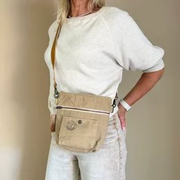 Beige cross-body bag with pockets and a straw hat, suitable for festivals or outdoor activities.