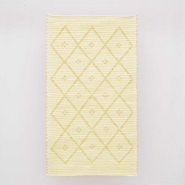Striped rug in yellow and white with a diamond pattern.