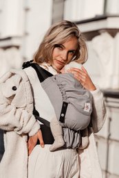 Gray baby carrier with adjustable straps and padding for comfort. Suitable for carrying infants and toddlers.