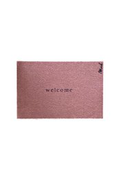 A rectangular brown doormat with the word "welcome" printed on it. The doormat is placed on a wooden floor, with a vase of flowers and other decorative items visible in the background.