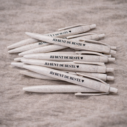  White pen with text "Tu es le meilleur" (You are the best) on a wooden background with flowers.