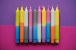 Colorful, cylindrical candles in various pastel shades including green, yellow, pink, and purple. The candles appear to be part of a "Neon '24 Collection" and are suitable for use as dinner candles.