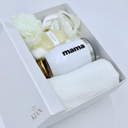White gift box with elegant wellness and beauty products, including a mug with the word "mama" printed on it.