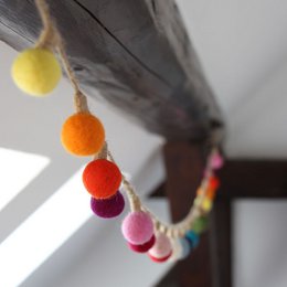 Colorful felt ball garland with assorted round felt balls in various bright colors including yellow, orange, red, pink, purple, and blue.