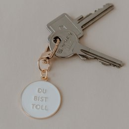 A set of 6 metal keychains with the text "Du bist toll" (You are great) printed on a white circular pendant.