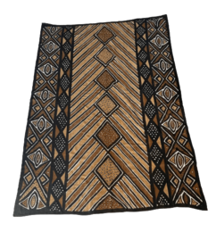 Large rectangular rug with intricate geometric patterns in shades of brown, black, and tan. The rug features a central diamond-shaped design surrounded by repeating diamond and triangle motifs. The materials appear to be woven or textured, creating a rich, earthy aesthetic.