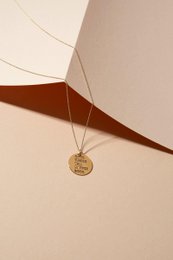  Gold-tone pendant necklace with circular medallion charm.
