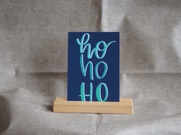 Navy blue greeting card with text "Ho ho ho" in light blue and green colors, suitable for Christmas.