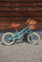 Pastel blue balance bike with wicker basket, suitable for storage and transportation.