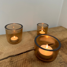  Large amber-colored glass tea light holder with a simple, cylindrical shape.