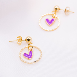  Gold-tone stud earrings with purple heart-shaped charms and circular hoops. Boho-inspired statement jewelry.