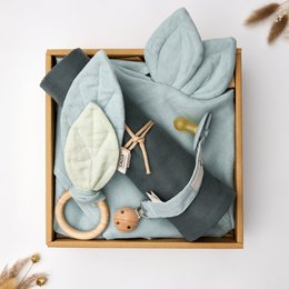  A gift box set containing a soft gray swaddle blanket, a wooden teething ring, and a plush animal toy in a neutral color palette.