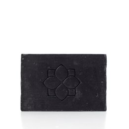 Black activated charcoal soap bar with floral embossed design, made with sandalwood, orange, and vetiver for cleansing and detoxifying skin.