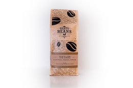 Organic coffee beans in a brown paper bag with the product name "The Taste" and coffee bean graphics. The bag appears to be made of recycled materials.