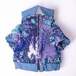 A vibrant, sequined pet jacket in shades of purple, blue, and green. The jacket has a hooded design and appears to be made of a durable, textured material.