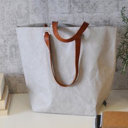 Reusable shopping bag made of eco-friendly material with leather handles. Available in multiple colors including brown, havana, grey, and black. Durable and stylish design suitable for everyday use.