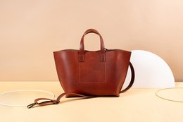Large brown leather tote bag with two handles and a detachable strap.