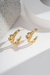  Textured gold-tone hoop earrings with a knot design, a trendy and original accessory made of stainless steel.