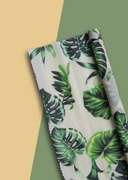 Tropical leaf-patterned food wrap roll, made of durable, reusable cloth material. Ideal for wrapping and storing food items.
