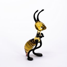 A decorative glass ant figurine with a yellow and black striped body and long antennae.
