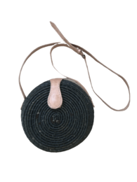 A black round crossbody bag with a long adjustable strap.
