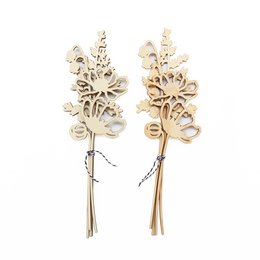 A decorative wooden bouquet of ferns and other natural elements, displayed in a glass vase on a windowsill.