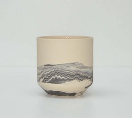 Black ceramic mug with abstract wave pattern design.