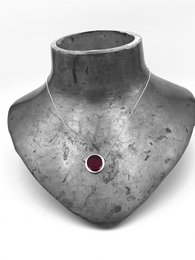 Simple small pendant with black or red chain, featuring a round red gemstone.