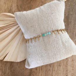 A delicate gold-toned bracelet featuring a row of turquoise-colored beads, creating a stylish and eye-catching accessory.