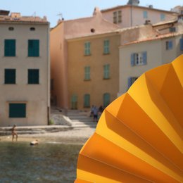  Orange translucent hand fan with a scenic coastal town in the background.