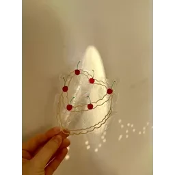  Vintage-style suncatcher with red beads and wire accents, creating a whimsical and decorative piece.