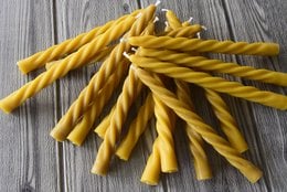 Twisted beeswax taper candle made of pure beeswax and cotton wick, in a yellow color with a spiral pattern.