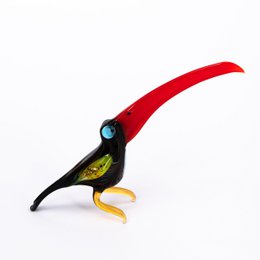 Glass toucan statue with vibrant red, black, and yellow colors depicting the distinctive beak and plumage of a tropical bird.