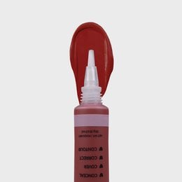 A concealer product with a red, liquid formula in a tube applicator. The concealer is designed to cover blemishes and imperfections on the face.