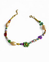 A colorful bracelet featuring green and pearl flowers.