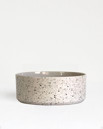  Sand speckled ceramic bowl, wide shallow shape, neutral beige with dark speckles, modern minimalist design.