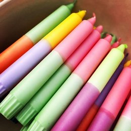 Colorful, cylindrical candles in various pastel shades including green, yellow, pink, and purple. The candles appear to be part of a "Neon '24 Collection" and are suitable for use as dinner candles.
